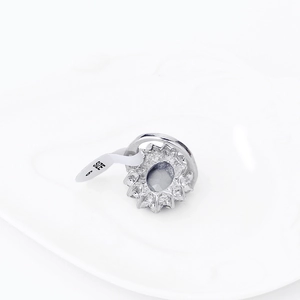 Oval sapphire ring in silver finish with halo diamonds and size 6 tag on white tray
