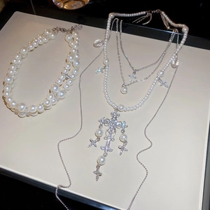 Detail of baroque pearl layers and sparkling zircon cross pendants on silver necklaces