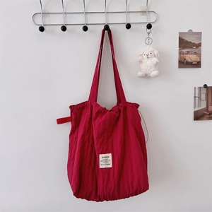 Detailed macro view of red canvas tote bag texture with minimalist white label and drawstring