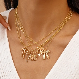 Détail de colliers dorés à plusieurs rangs avec pendentifs nœuds délicats portés au cou