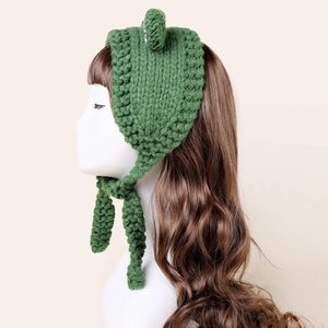 Detail view of the hand-knitted green frog hat with eye decorations and ear flaps