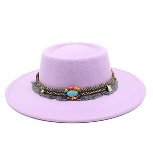 Détail d'un chapeau en feutre violet avec bande tissée colorée et pierre turquoise