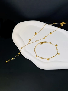 Flat lay of 18K gold plated stainless steel bead tassel necklace and bracelet set