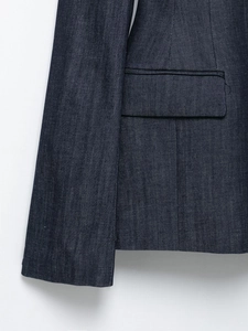 Dettaglio della manica e della tasca con patta della giacca di jeans blu scuro