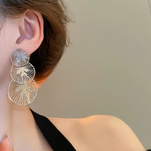 Gros plan de boucles d'oreilles argentées à trois cercles évidés aux textures rayonnantes