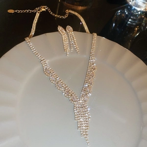 Close-up of sparkling crystal pendant and earrings set on white ceramic plate
