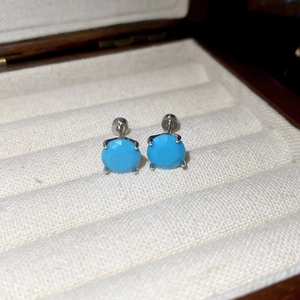 Macro shot of turquoise zircon studs with silver claw setting in a jewelry box