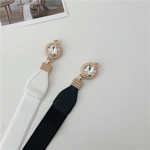 Detail of elastic waist belts in black and white with gold crystal buckles