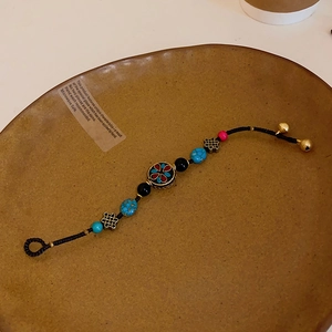 Détail d'un bracelet tissé ethnique avec des perles colorées et des petites cloches dorées