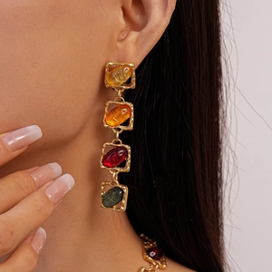 Close-up of retro gold geometric earrings with colorful amber and resin resin inlays