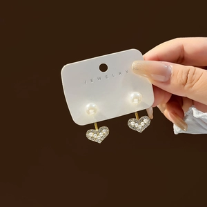 Detailed view of gold heart earrings with white pearls and sparkling rhinestones