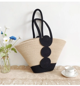 Detail of woven cotton tote bag with black decorative rings on lace tablecloth