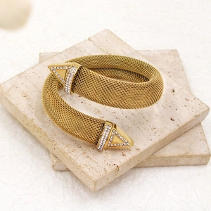 Detail of gold mesh cuff bracelet with sparkling triangle accents on stone tray