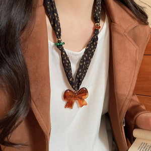 Close-up of fabric neckband with polka dots and large amber acrylic bow pendant necklace