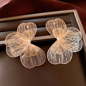 Macro shot of gold hollow petal earrings on a dark display tray for a vintage aesthetic