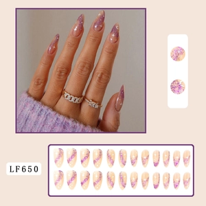 Detail of almond nails with nude base, purple glitter swirls, and star moon patterns
