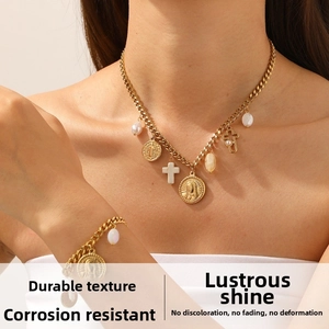 Detail of vintage gold-plated necklace set with pearl, cross, and religious oval charms