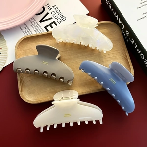 Set of four French acetate hair claws in ink blue and beige on a wooden tray