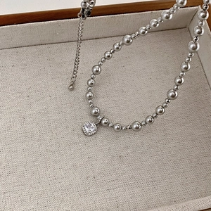 Detailed macro view of square zircon pendant and mixed size pearls on luxury necklace
