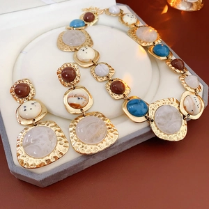 Detail view of vintage geometric gold jewelry set with colorful resin stones in a gift box