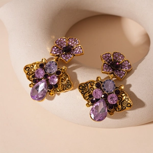 Detailed close-up of retro gold-finish flower earrings with purple teardrop crystals