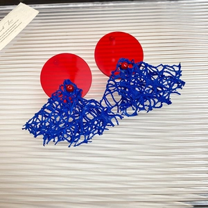 Détail de boucles d'oreilles en maille rouge et bleue avec disques en acrylique