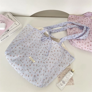 Detailed macro view of floral chiffon tote bags in grey-blue and pink on a desk