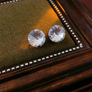 Close-up of sparkling heart stud earrings on vintage green velvet display padding