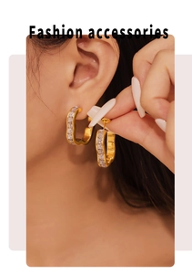 Detail showing gold-plated flower earrings with square zircon on a female model