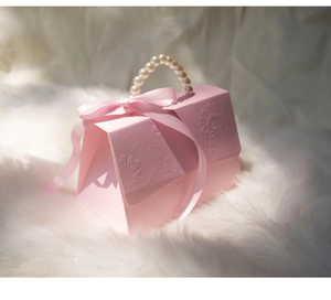 Detailed view of pink floral embossed candy box with pearl handle and ribbon bow