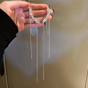 Détail de manchette d'oreille argentée à longues franges en métal texturé et strass