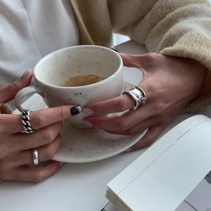 Detail shot of chunky irregular silver ring worn while holding a ceramic coffee cup