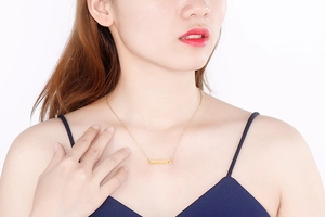 Minimalist gold bar pendant necklace shown on a model with a heart-shaped inlay detail