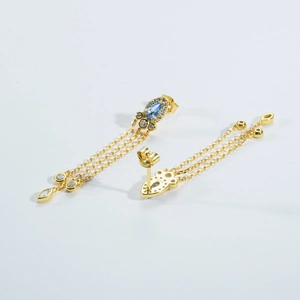 Macro shot of S925 silver earrings with pear blue crystal and golden tassels
