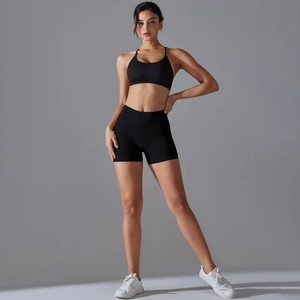 Detail of seamless black cross-back sports bra and high-waist shorts set in studio light