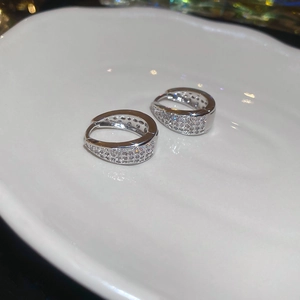 Macro shot of silver U-shaped earrings with micro-pave cubic zirconia in a white tray