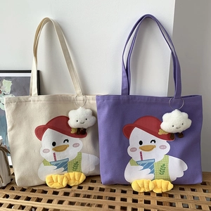 Detail of canvas tote bags with cartoon duck illustration and plush cloud pendant accessory