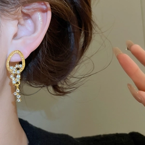 Close-up of elegant gold tassel earrings with diamond accents worn by a model