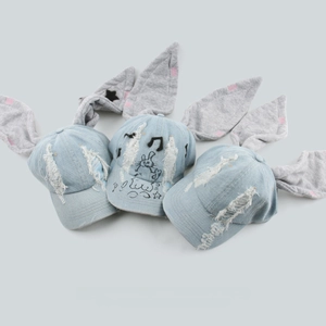 Detail der hellblauen Denim-Baseballkappe mit grauen Hasenohren und Graffiti-Grafiken