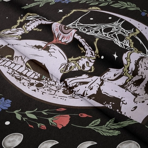 Detail of gothic tapestry showing skull, crescent moon and floral patterns on black fabric