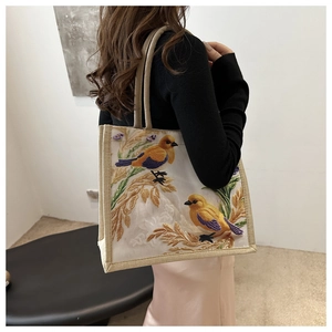 Detailaufnahme der Vintage-Tragetasche mit Blumenstickerei und goldener Vogelverzierung