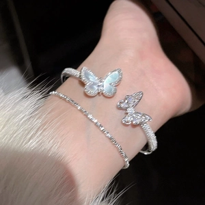 Macro detail of silver butterfly bangle with shell inlay and zircon crystals on faux fur