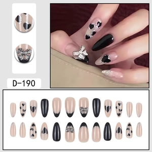 Elegantes uñas postizas de almendra con corazones negros y dijes de lazo plateado brillante