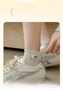 Detailed embroidery of a cartoon dog on beige ribbed cotton socks with elastic cuffs