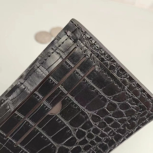 Macro detail of men's crocodile textured leather wallet showing multiple card slots