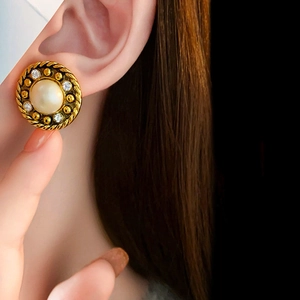 Gros plan sur une boucle d'oreille vintage dorée avec perle et cristaux scintillants