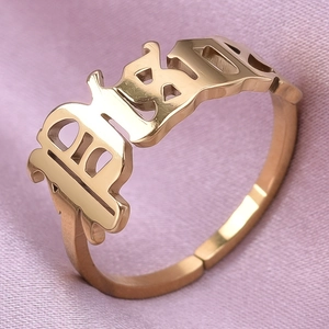 Detail of adjustable gold ring featuring Gothic Baby lettering on purple silk surface
