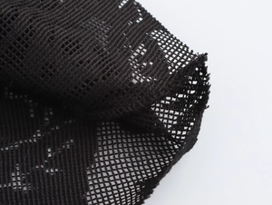 Close-up of black mesh knit fabric showing detailed hollow out texture and stitching