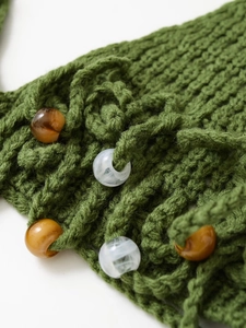 Macro detail of green knit fabric featuring amber and marble-patterned resin beads