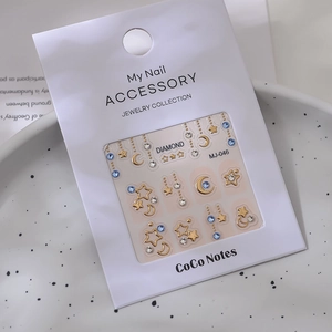 Detailed view of 3D nail art stickers with gold stars and blue rhinestones in a tray